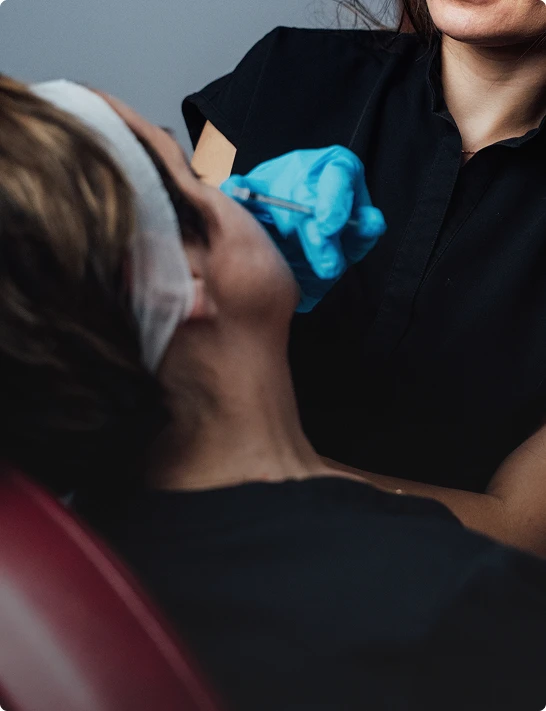 Dentist examining patient's teeth while wearing blue gloves in dental clinic