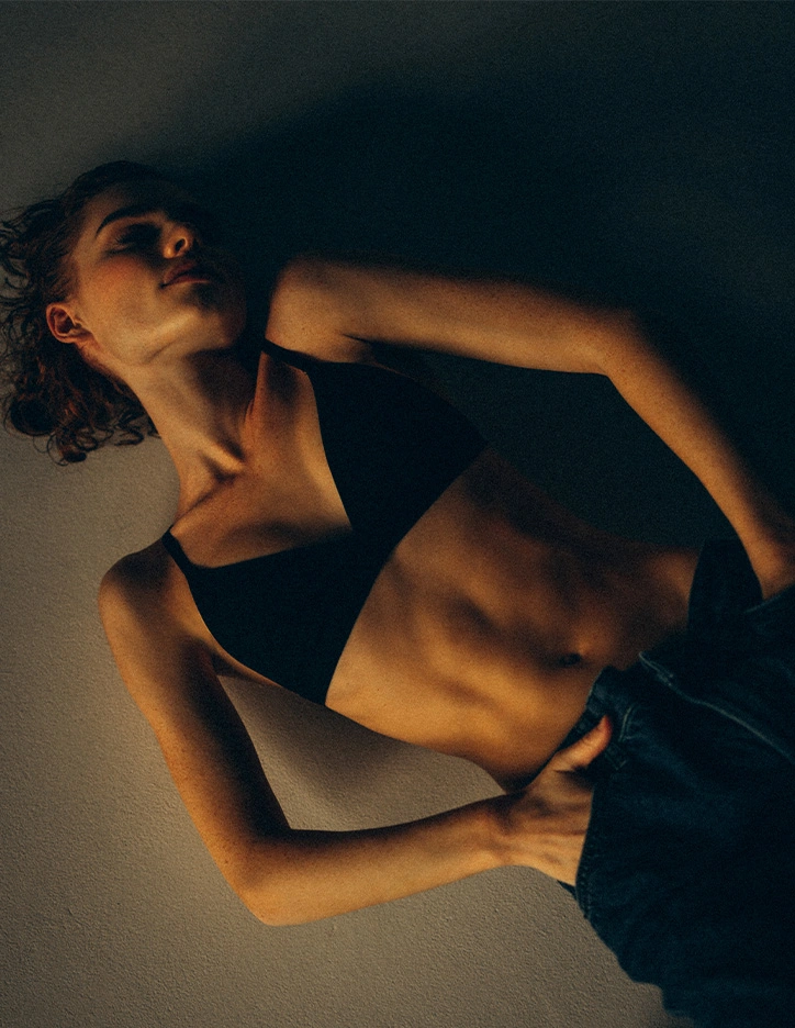 Artistic portrait of woman in black athletic wear lying down with dramatic shadow lighting