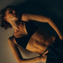 Athletic woman in black sports bra showing toned abs and fitness physique in dramatic lighting