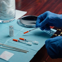Laboratory technician in blue gloves handling medical samples and testing equipment on sterile blue surface