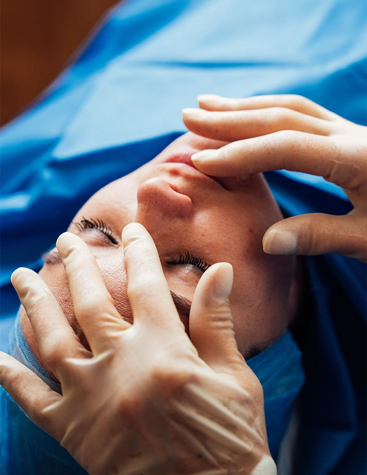 Surgeon performing rhinoplasty surgery on patient in operating room with surgical instruments