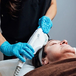 Esthetician performing facial treatment with handheld device on client wearing blue gloves in spa setting - Skin Tightening incl info for Sofware Treatment/ Ultherapy in Chicago, IL