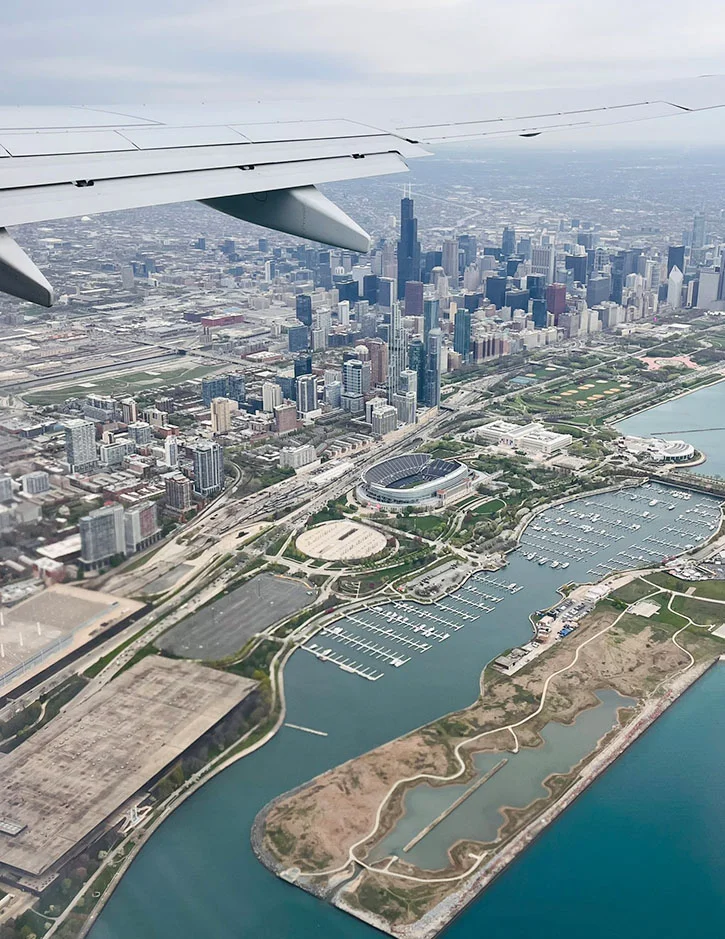 Aerial view of Chicago skyline and Lake Michigan from airplane window showing downtown skyscrapers and waterfront